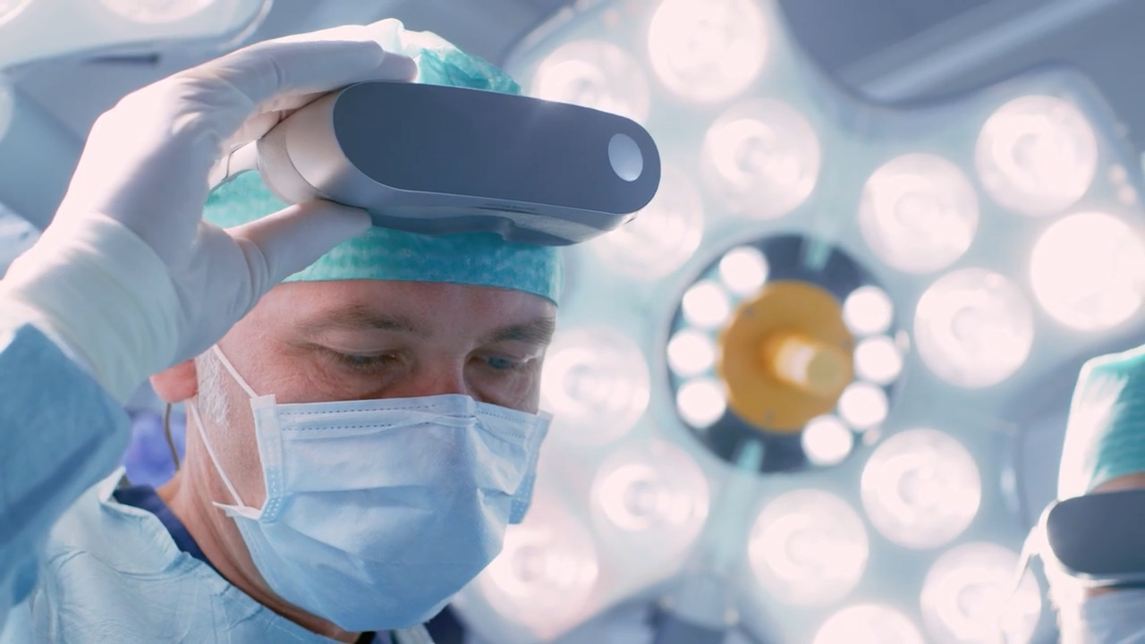 Nahaufnahme eines Chirurgen vor Licht mit Lupenbrille auf seinem Kopf