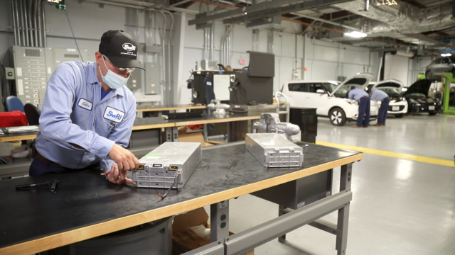 Mechanic inspecting an electric car battery pack in a modern workshop