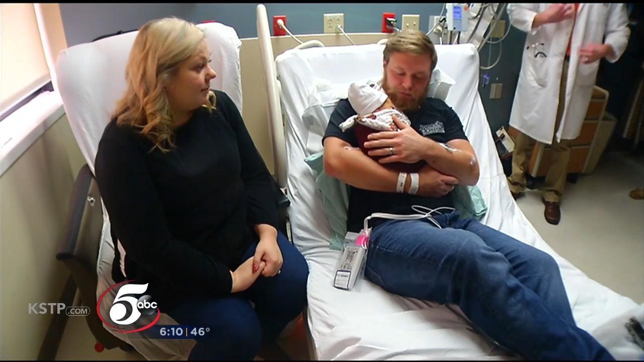 In this Tuesday, Oct. 23, 2018, photo Andrew Goette and his wife, Ashley,  look at their baby, Lennon, at United Hospital in Saint Paul, Minn. Andrew  awoke from a medically-induced coma just