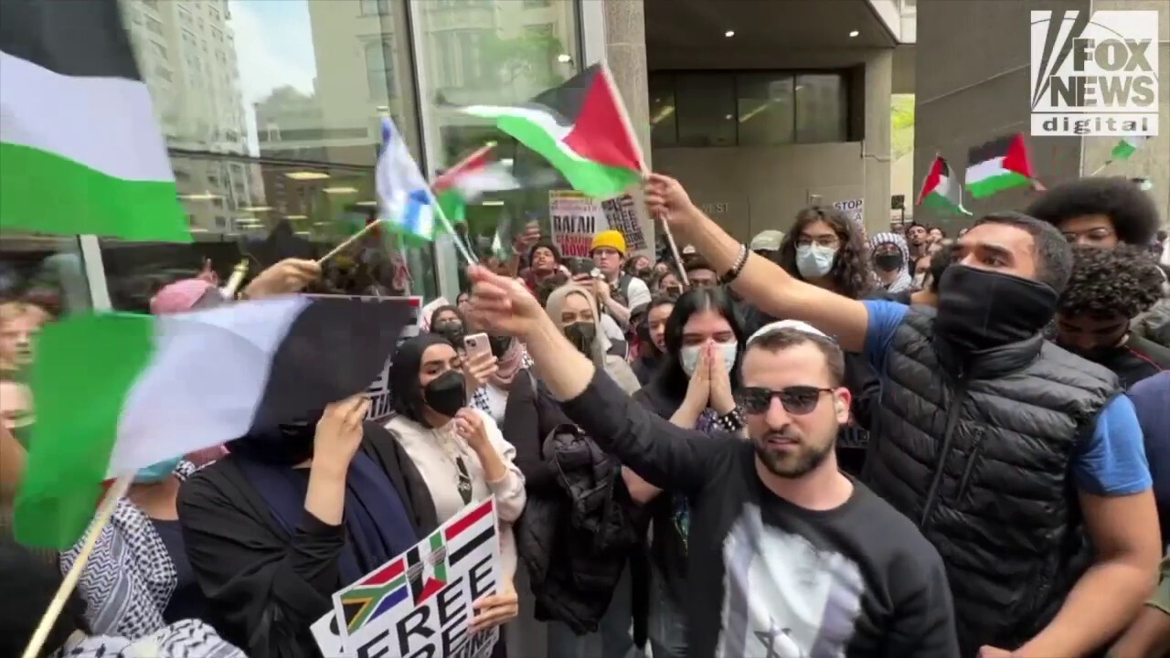Тълпа от анти израелски протестиращи развяващи палестински знамена в Горен Ийст