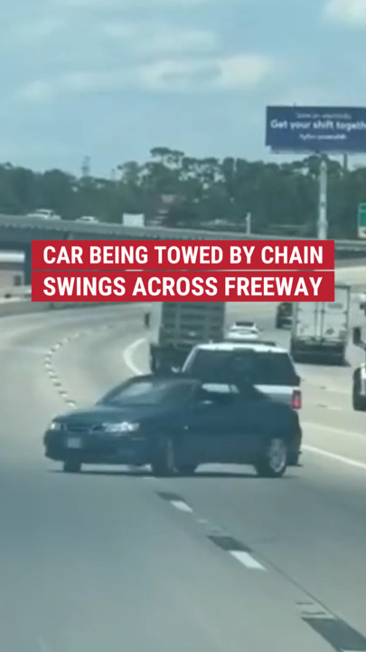 Wild moment caught on cam of a car being towed with only chain swerves out of control on a freeway