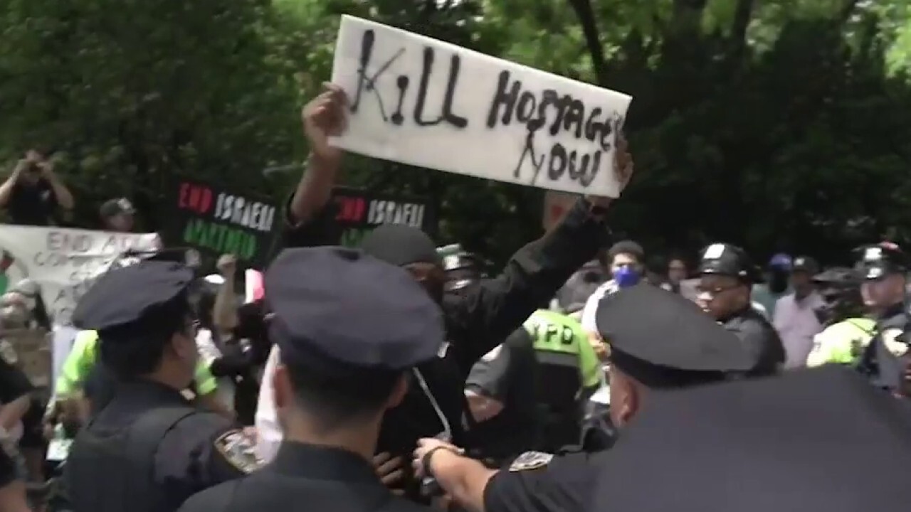 Маскиран протестиращ вдига надпис „Убийте заложниците сега“ по време на парада за Деня на Израел в Ню Йорк
