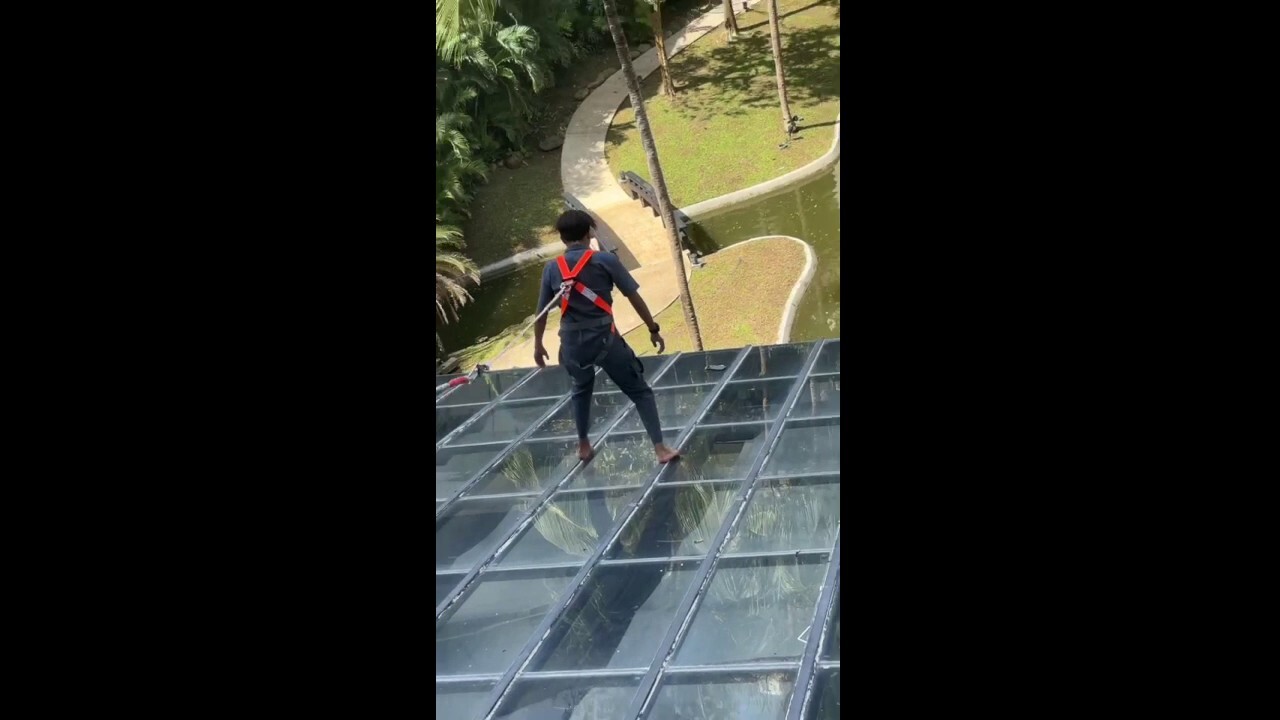 Hotel employee bravely retrieves guest's cell phone from glass roof 