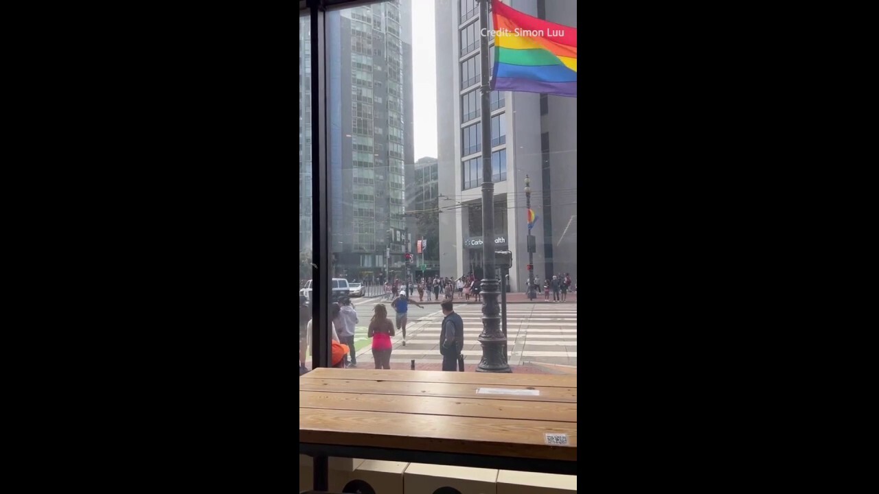 Man runs across the street in a panic as what sounded like shots are heard during San Francisco Pride event