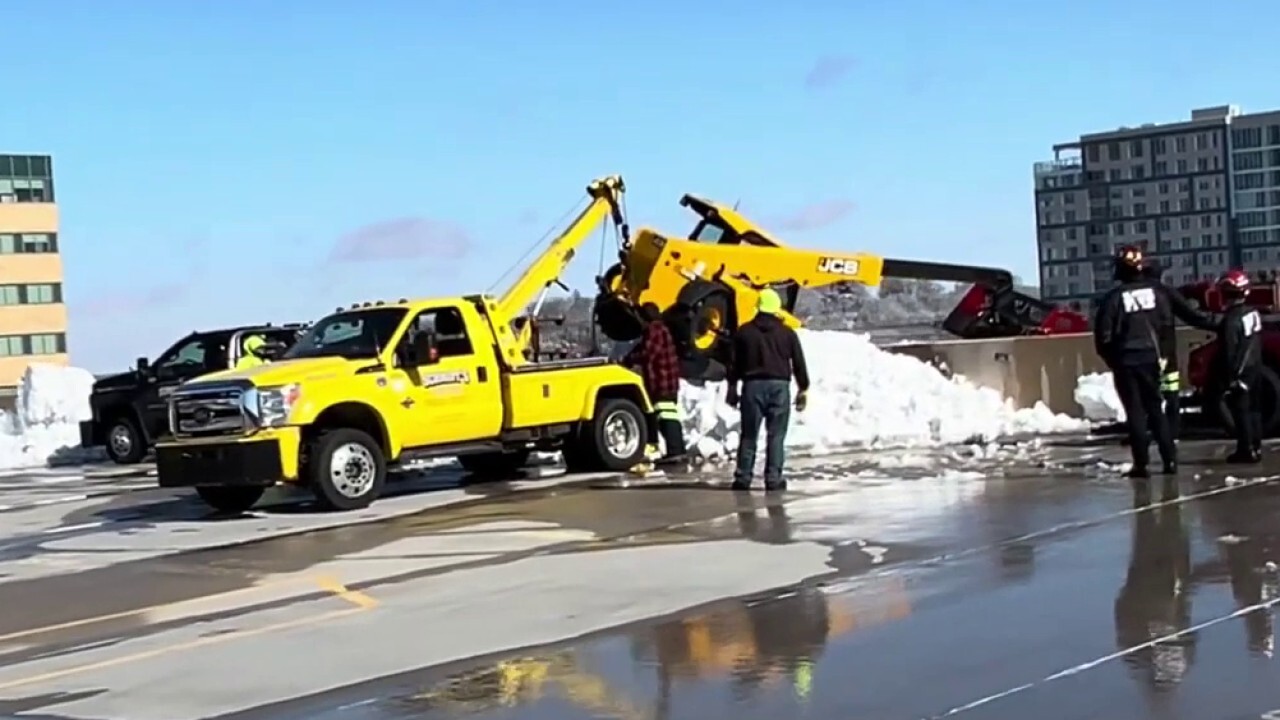 Видео показва тежко оборудване, увиснало от паркинг-гараж в Уисконсин, след като се преобърна, докато чисти сняг