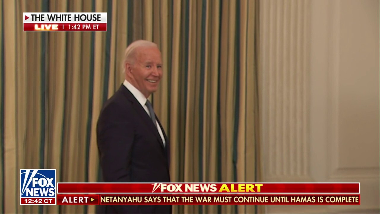 Biden smiles after a reporter asks about the Trump case